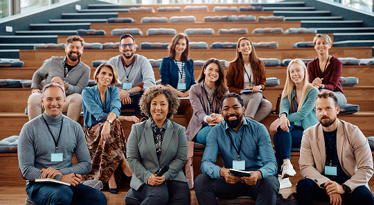 Picture of 12 people, sitting on wooden bleachers, all with name tags, as in a part of a conference