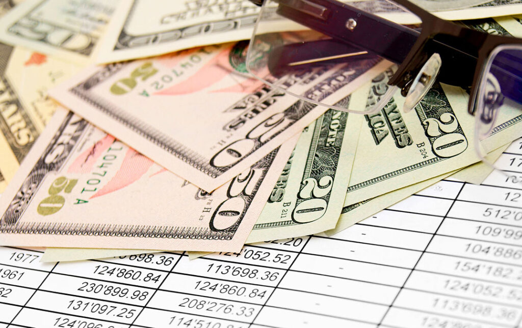 Picture of dollar bills on top of a page containing numbers